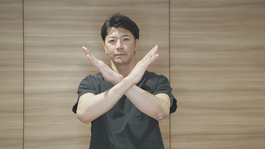 顔の前でバツをつくる竹江総院長